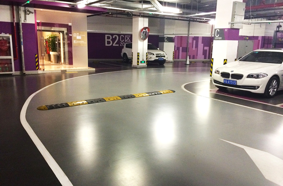 Indoor basement car park with grey epoxy floor, white markings and parked cars