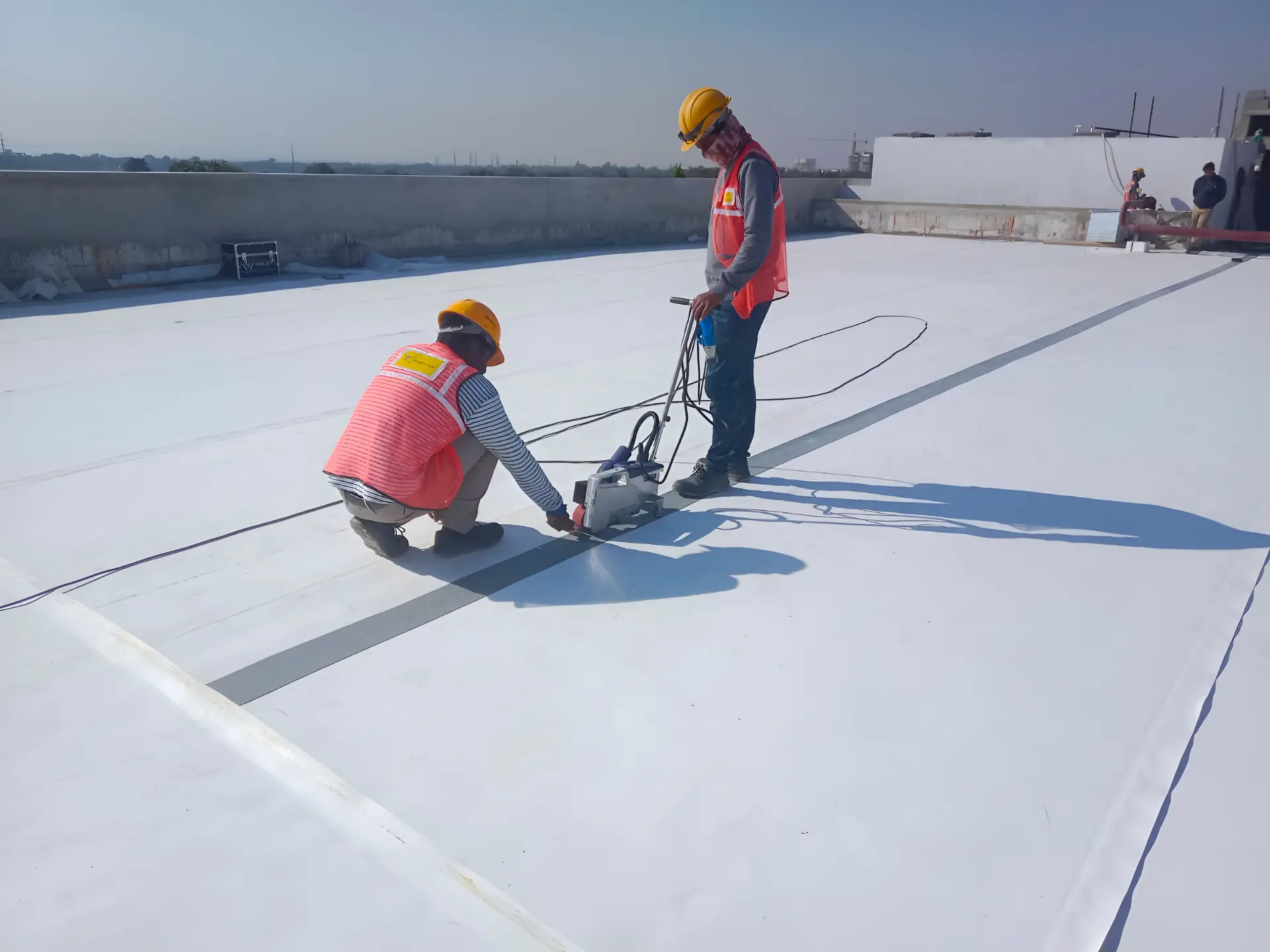 WrapPro crew hot-air welding TPO membrane seams on a large white terrace roof