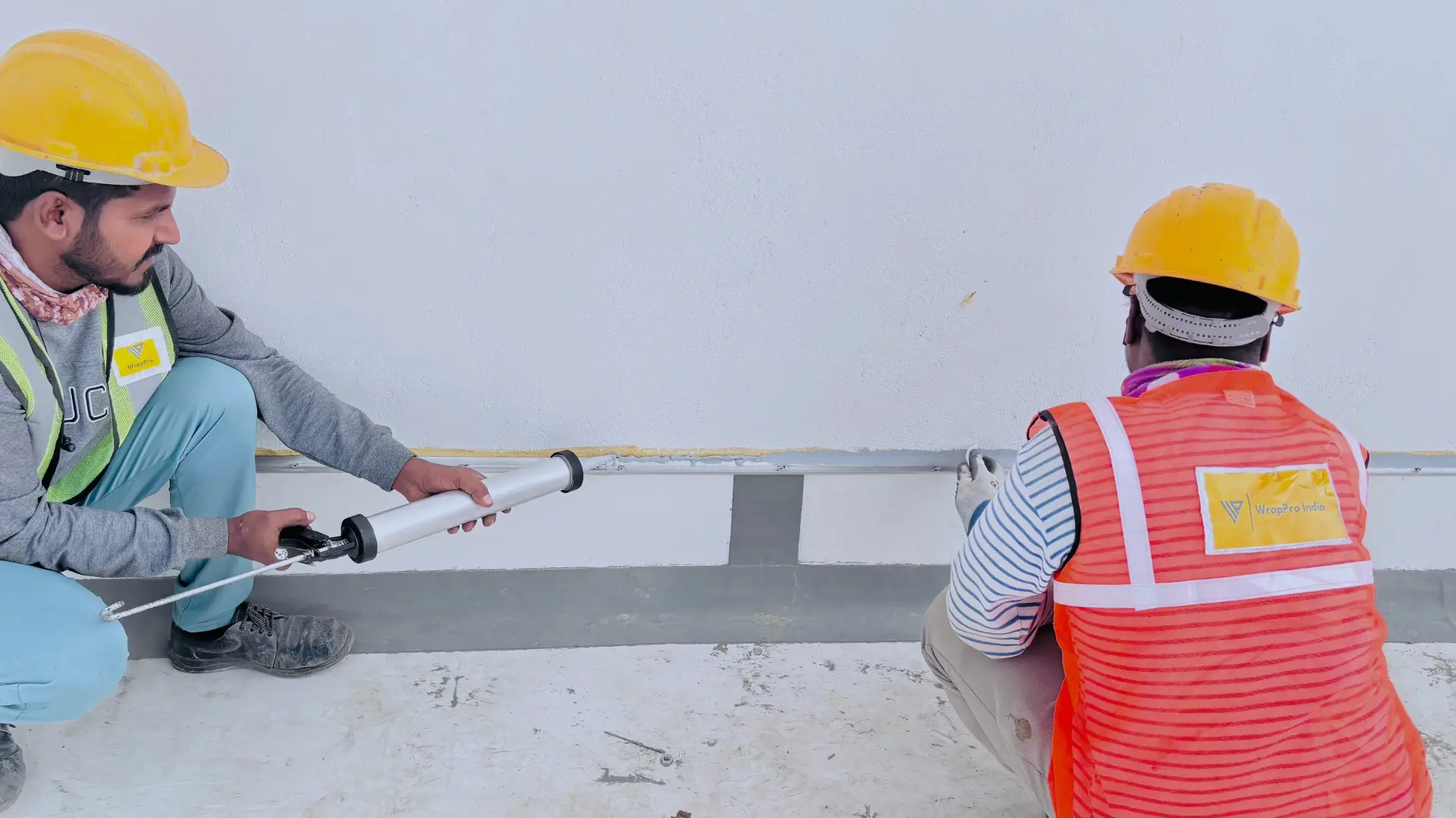 WrapPro crew applying PU sealant to the parapet wall termination joint on a waterproofed terrace