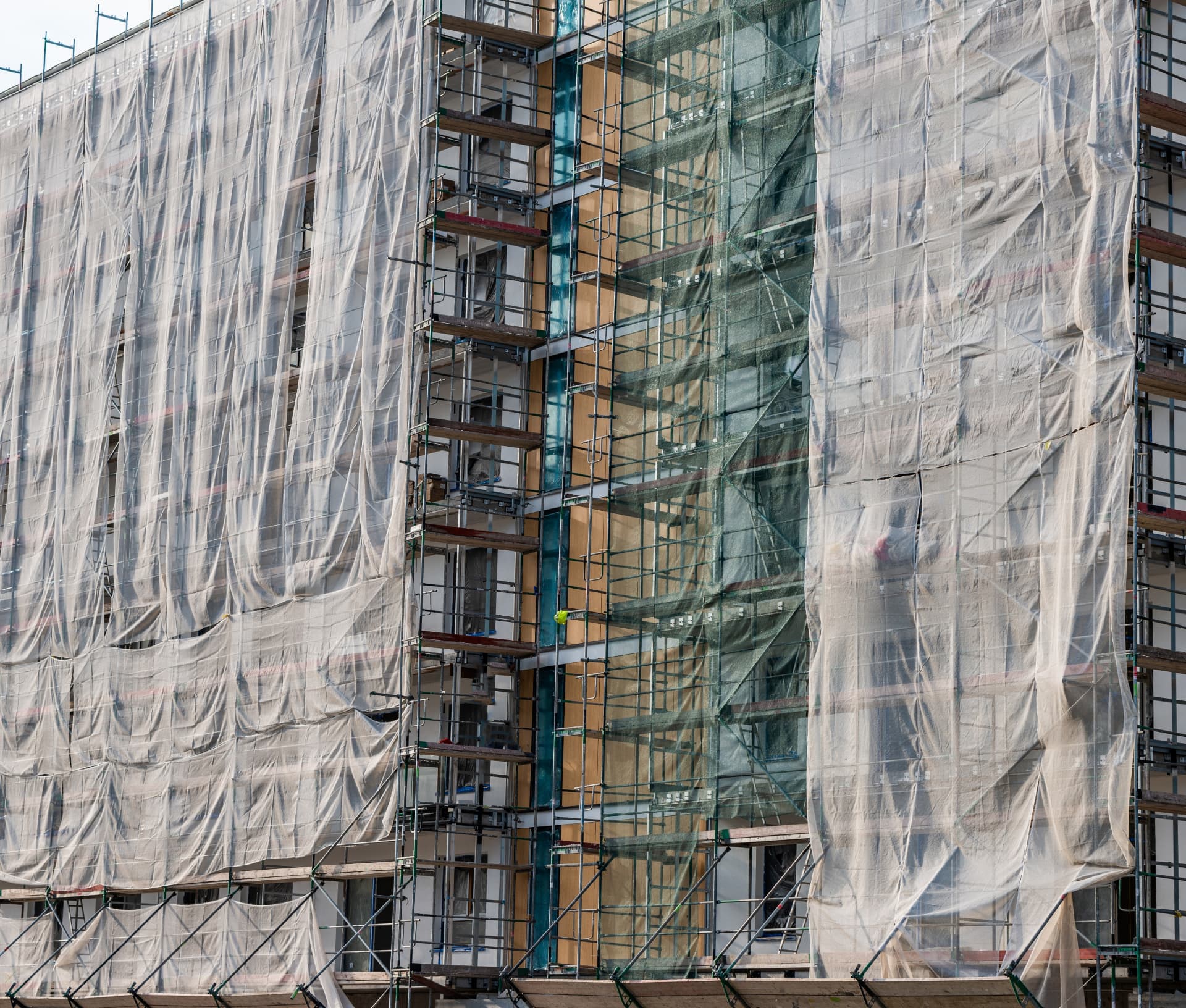 Building façade under repair with scaffolding and protective sheeting during restoration work
