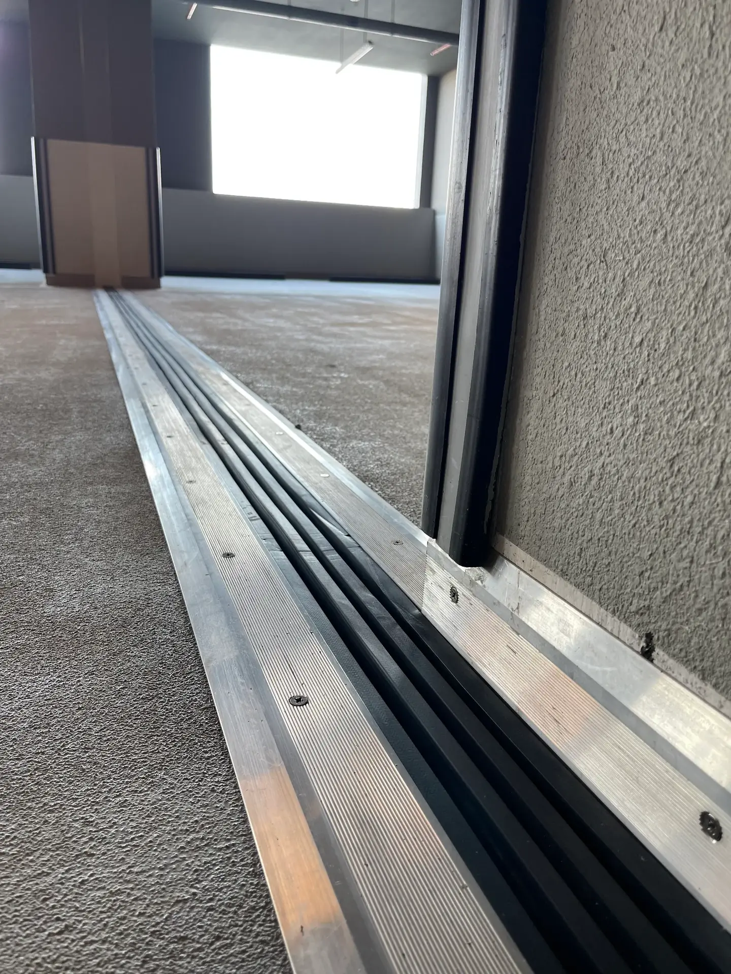 Aluminium expansion joint cover plate installed flush across a finished interior floor